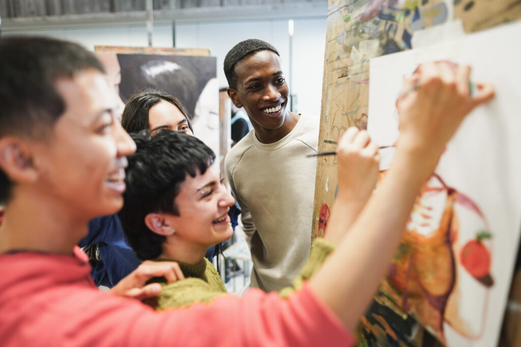 Multiracial students painting inside art room class at school