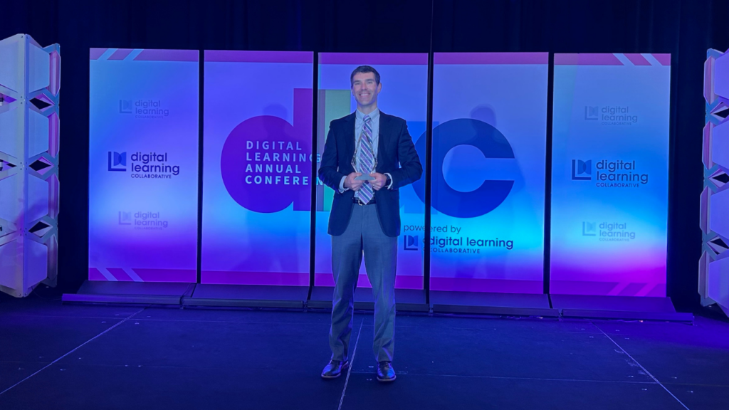 Joseph R. Friedhoff holding the 2024 Digital Learning Collaborative (DLC) Research Impact Award